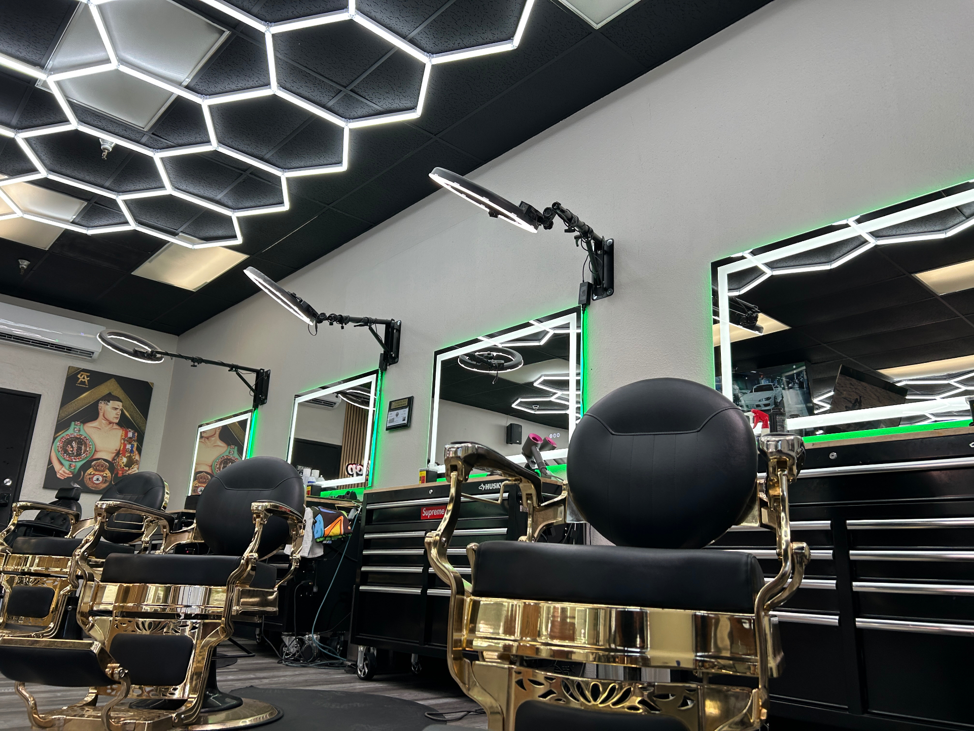 Gold barber chairs under hexagon ceiling lights at dbarbershop